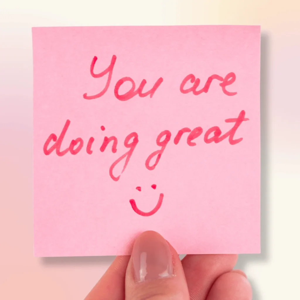 A hand holding a pink post it note that says You are doing great. Positive Affirmations For Friendships