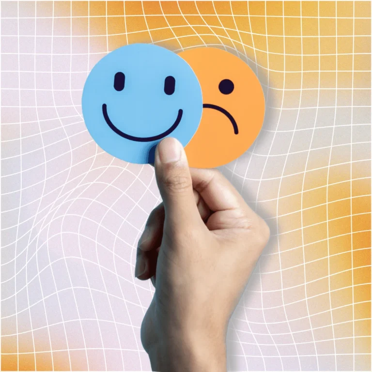 A hand holding up a two round cards of a happy face and a sad face. How to Set Healthy Boundaries With Friends