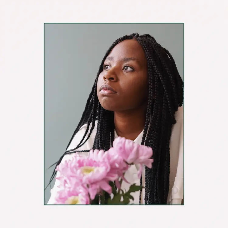 Pensive young African American lady with flower bouquet looking away dreamily