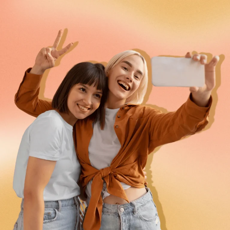 Two friends posing for selfie. Background is an orange and peach gradient