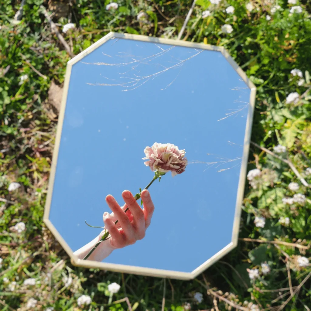 Hand with Flower Reflected in Mirror. 