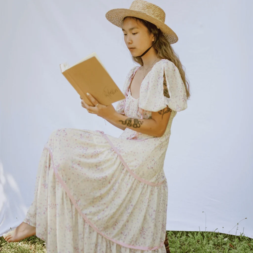 self-compassion journal prompts. Woman in a summer dress reading