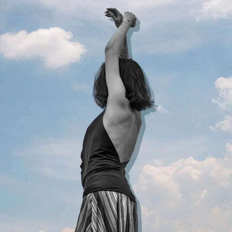 Anonymous woman raising her hands against cloudy sky. Self-Care Sundays