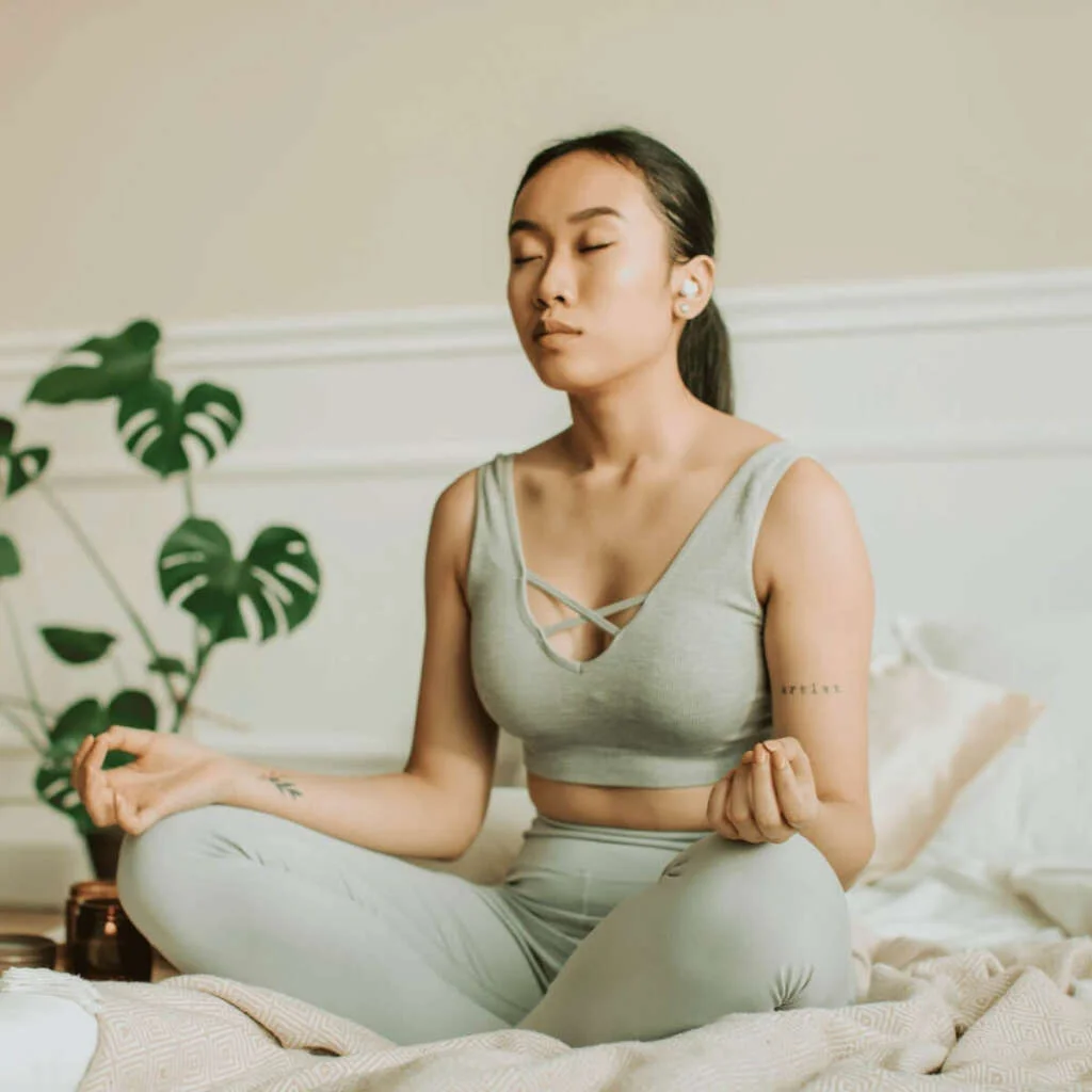 Asian women meditating in a grey crop top and matching leggings. Self-Care Sundays