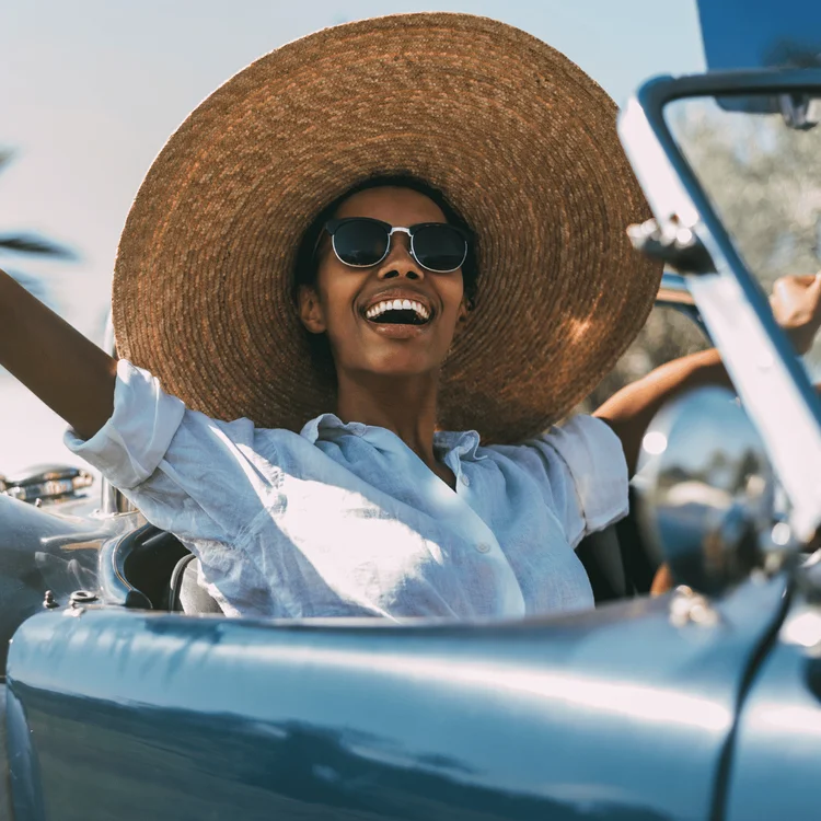 Black woman driving a vintage convertible car. Saturday selfcare ideas