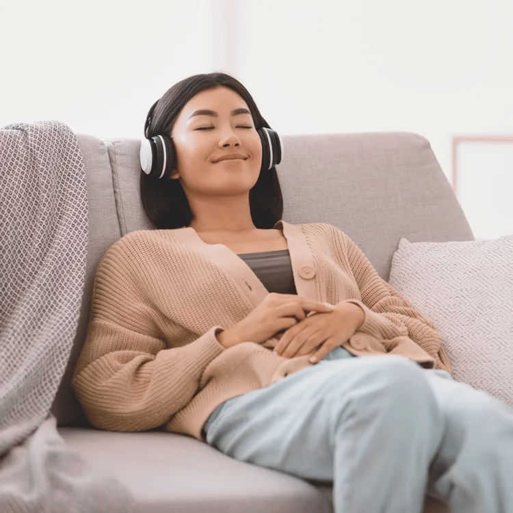 Calm Asian woman listening to music wearing headphones