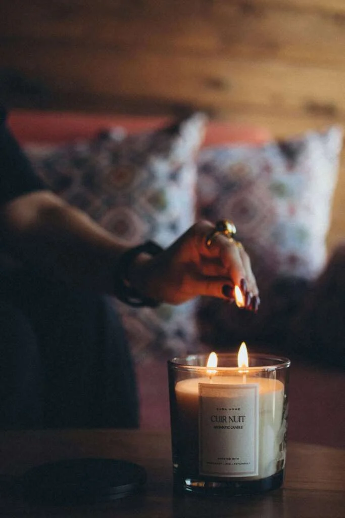 Person lighting a candle in a dimly lit room. Saturday self-care routine