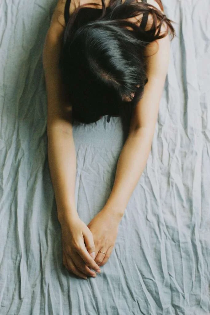 Woman stretching her arms out on her bed. Saturday self-care routine