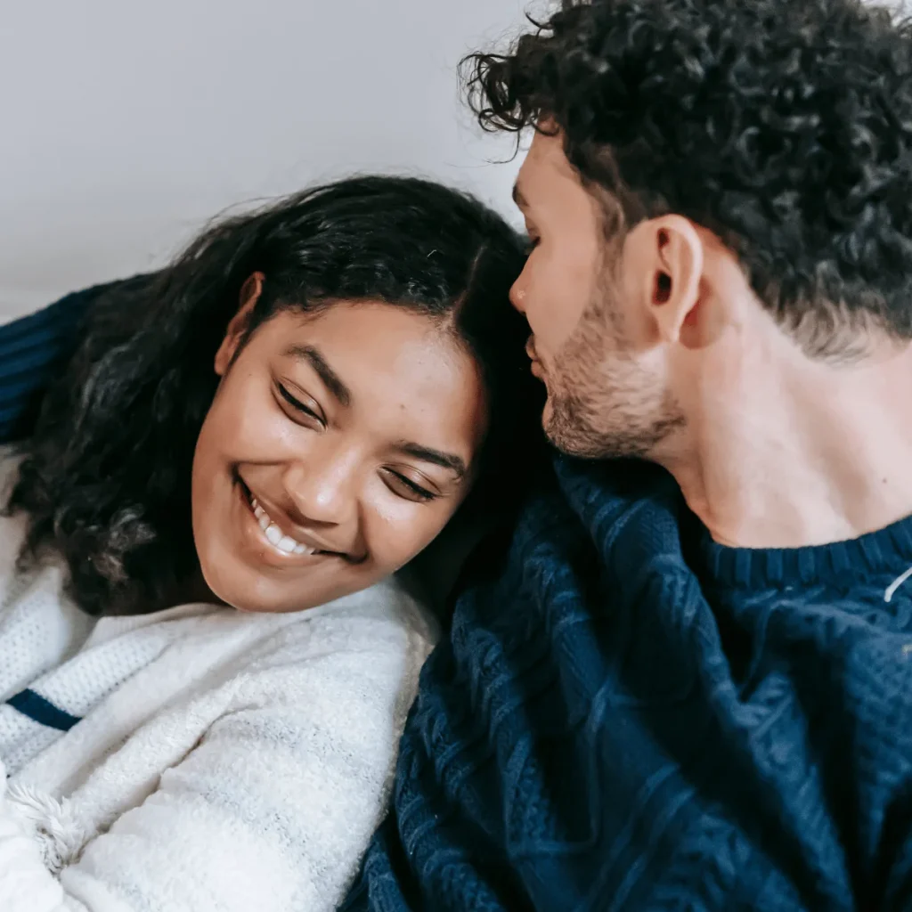 Young couple snuggled up and smiling. Affirmations To Attract Love