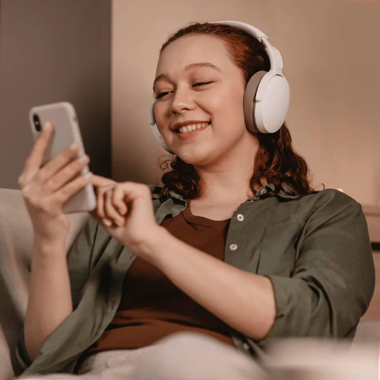 woman using modern headphones smartphone devices of a home. Saturday selfcare ideas