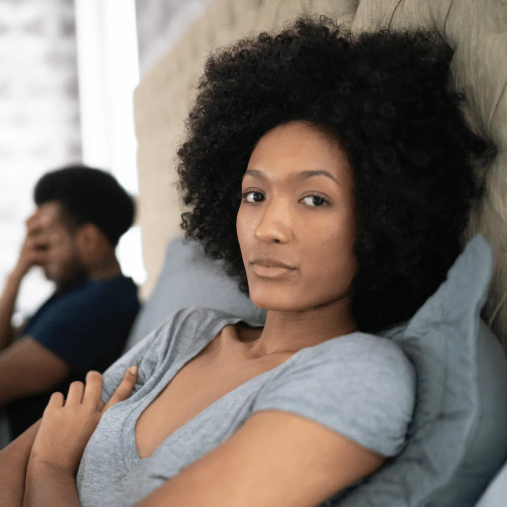 Woman-with-afro-looks-fed-up-she-is-sitting-up-beside-her-partner-in-bed. Wounded Feminine Energy