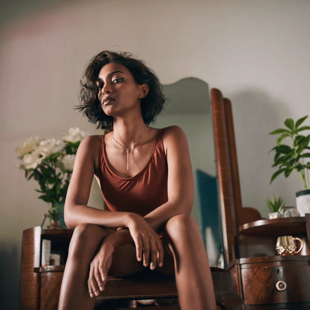 Strong-woman-sitting-down-in-a-dimly-lit-room-staring-at-the-camera