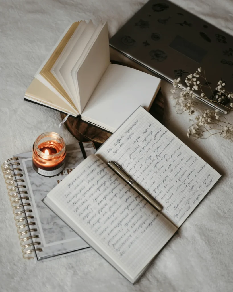 journals on a bed with a candle and flowers